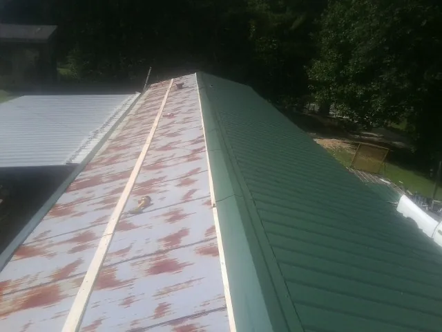 Old rusted panels beside newly installed green metal roofing — Wind Damage Roof Repair by Roofing Brothers in Wilder