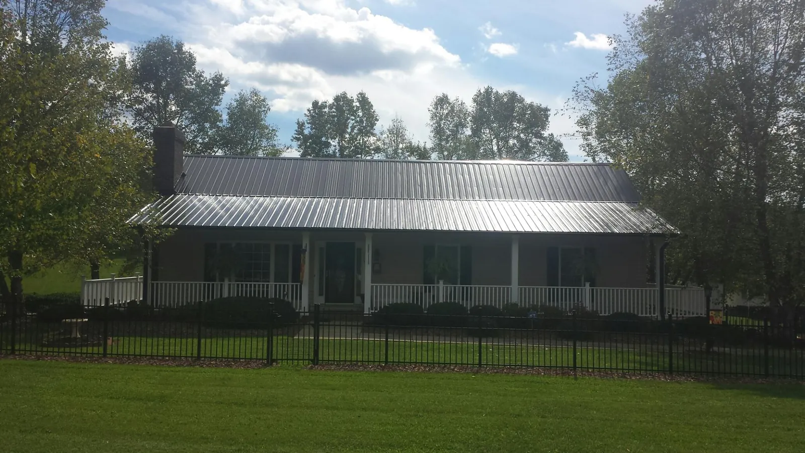 Gray metal roof on a brick ranch with a full width front porch — Gutter Guard Installation work by our crew in Wilder