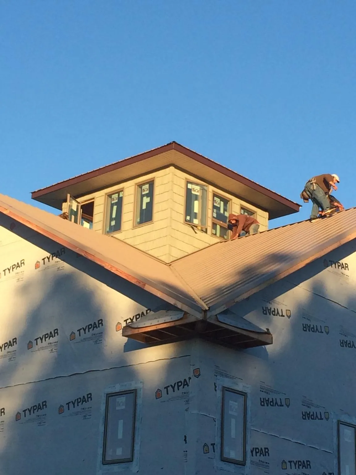 Roofers working around a rooftop cupola on a new metal roof at sunset — Roof Waterproofing in Wilder by Roofing Brothers